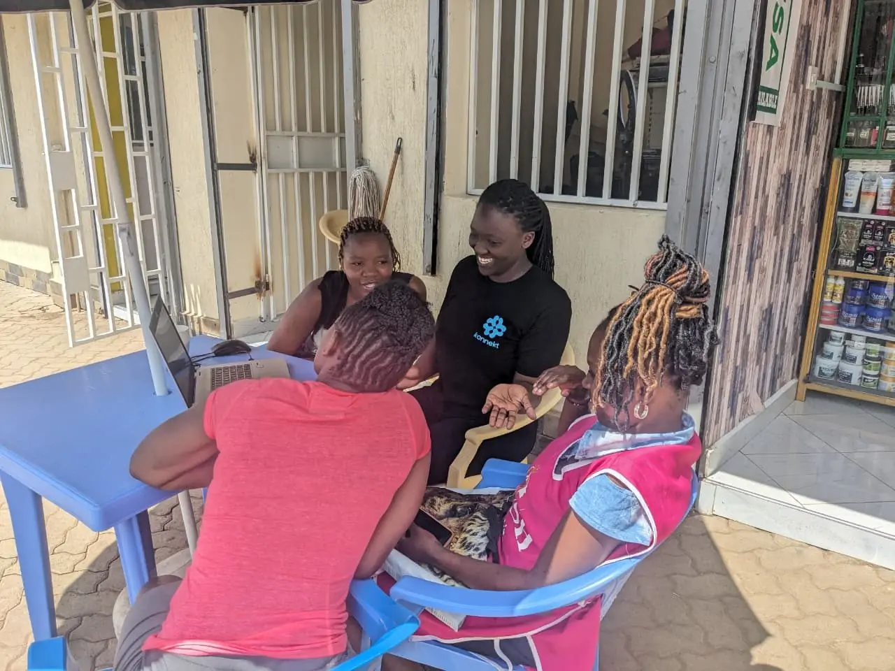 A konnekt Academy facilitator coaches women on their phones at an outdoor pop-up session